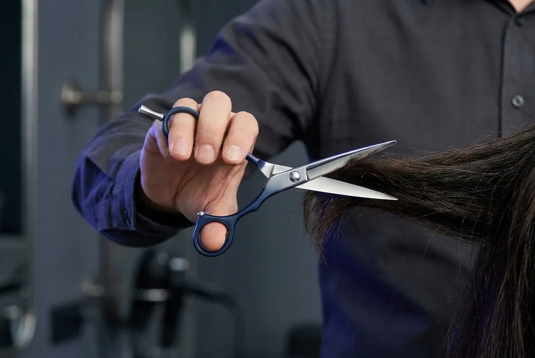 Thợ tóc cầm kéo cắt một lọn tóc